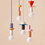 Set of five Nordic-style wooden pendant lights in orange, cream, blue, pink, and red with exposed bulbs and geometric shapes.