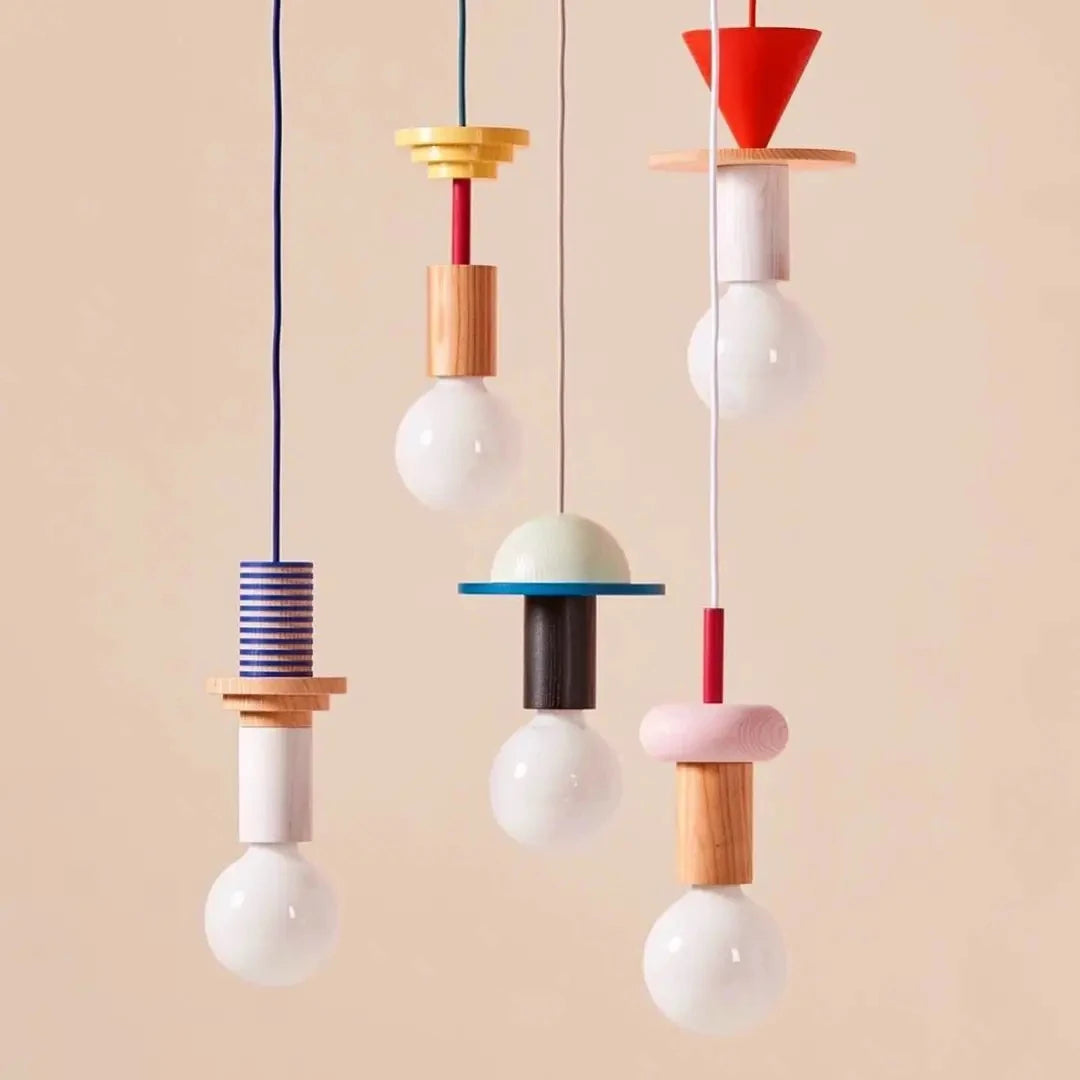 Set of five Nordic-style wooden pendant lights in orange, cream, blue, pink, and red with exposed bulbs and geometric shapes.