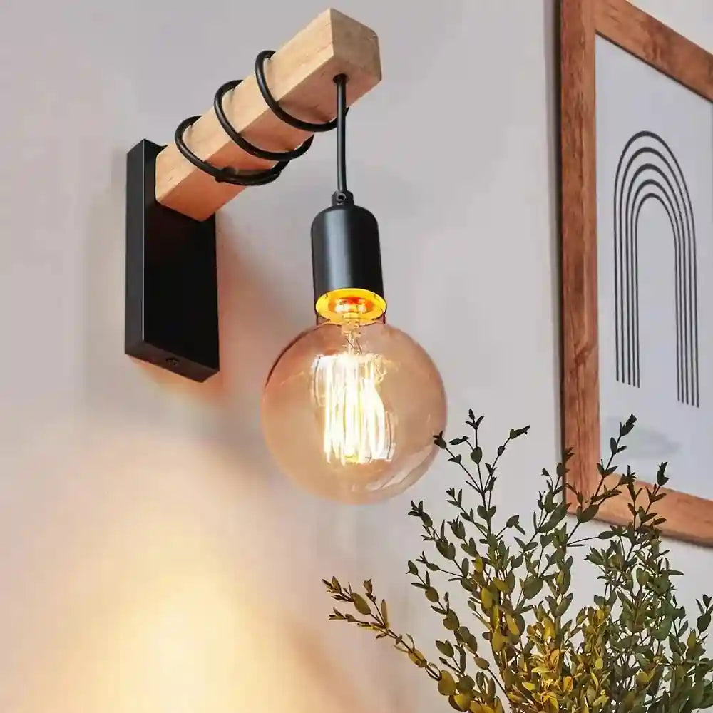 Black industrial wall lamp with wooden beam and exposed LED filament bulb.