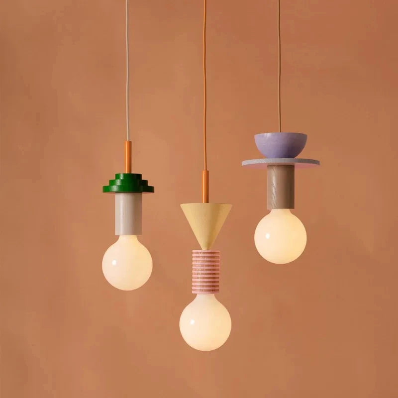 Three modern wooden pendant lights with geometric shapes in green, beige, and lavender, suspended on orange cords against a.