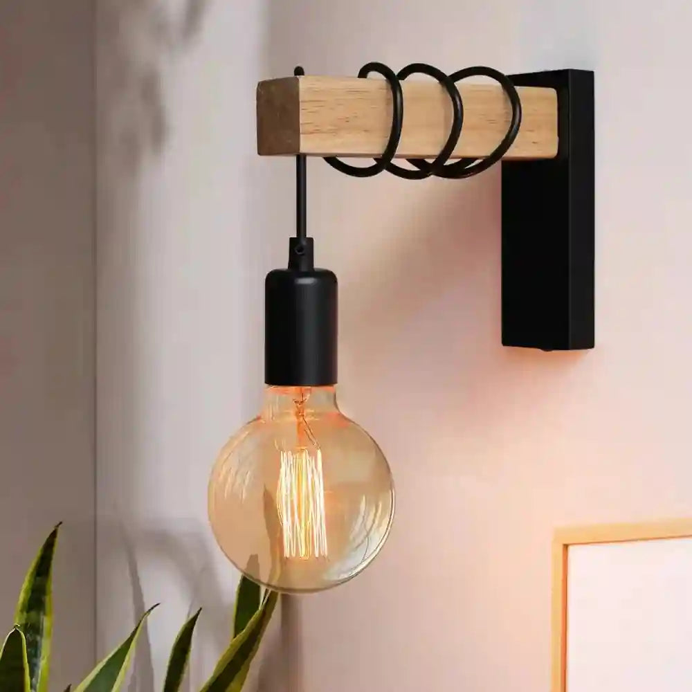 Black industrial wall lamp with wooden horizontal mount and exposed vintage LED bulb.