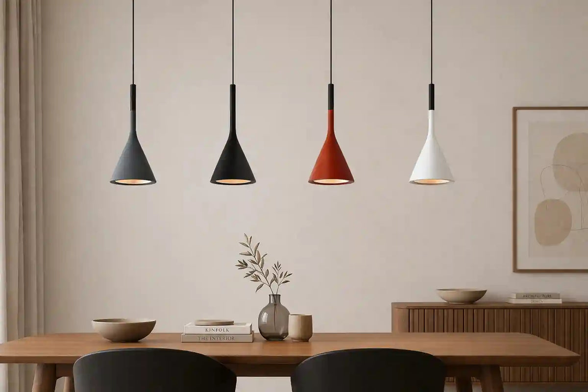 Four modern pendant lights in black, red, and white matte finishes hanging above a wooden dining table.