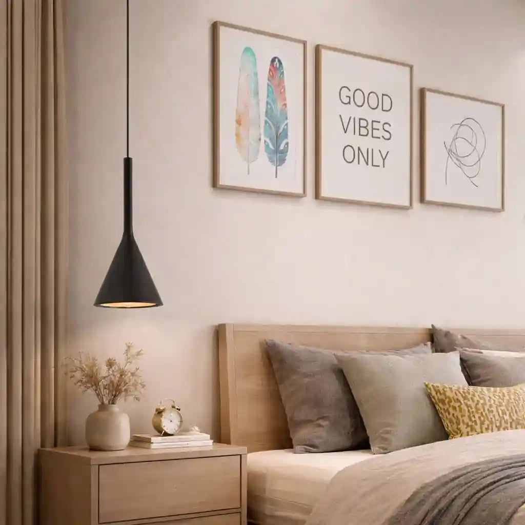Black conical pendant light with warm glow over wooden bedside table in neutral bedroom setting.